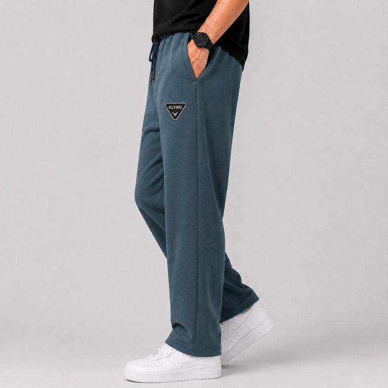 KLYRO FASHION blue oversized sweatpants with a triangular logo patch, worn with white sneakers.