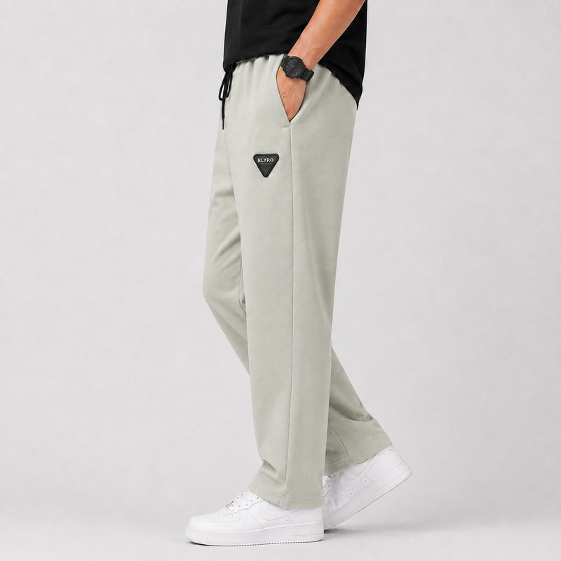KLYRO FASHION men's light grey relaxed track pants with a black drawstring waist and a triangular logo patch